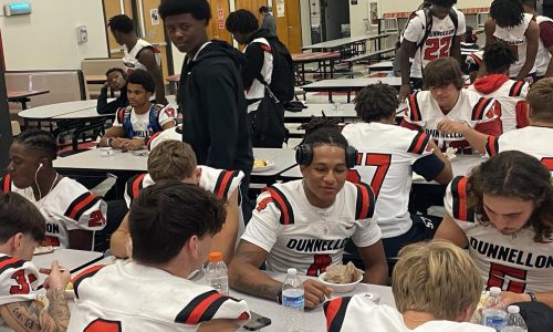 student athletes sit and eat food before a home game